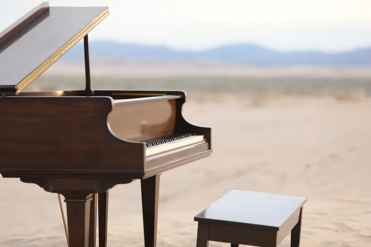 Detail shot of a vintage Kimball grand piano staged on Little Sahara sand dunes for a Safe and Sound Pianos music video.