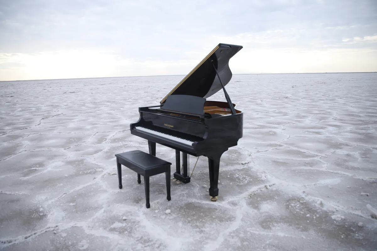 Black grand piano on a downtown Salt Lake City rooftop, the lid open and skyline filling the background.
