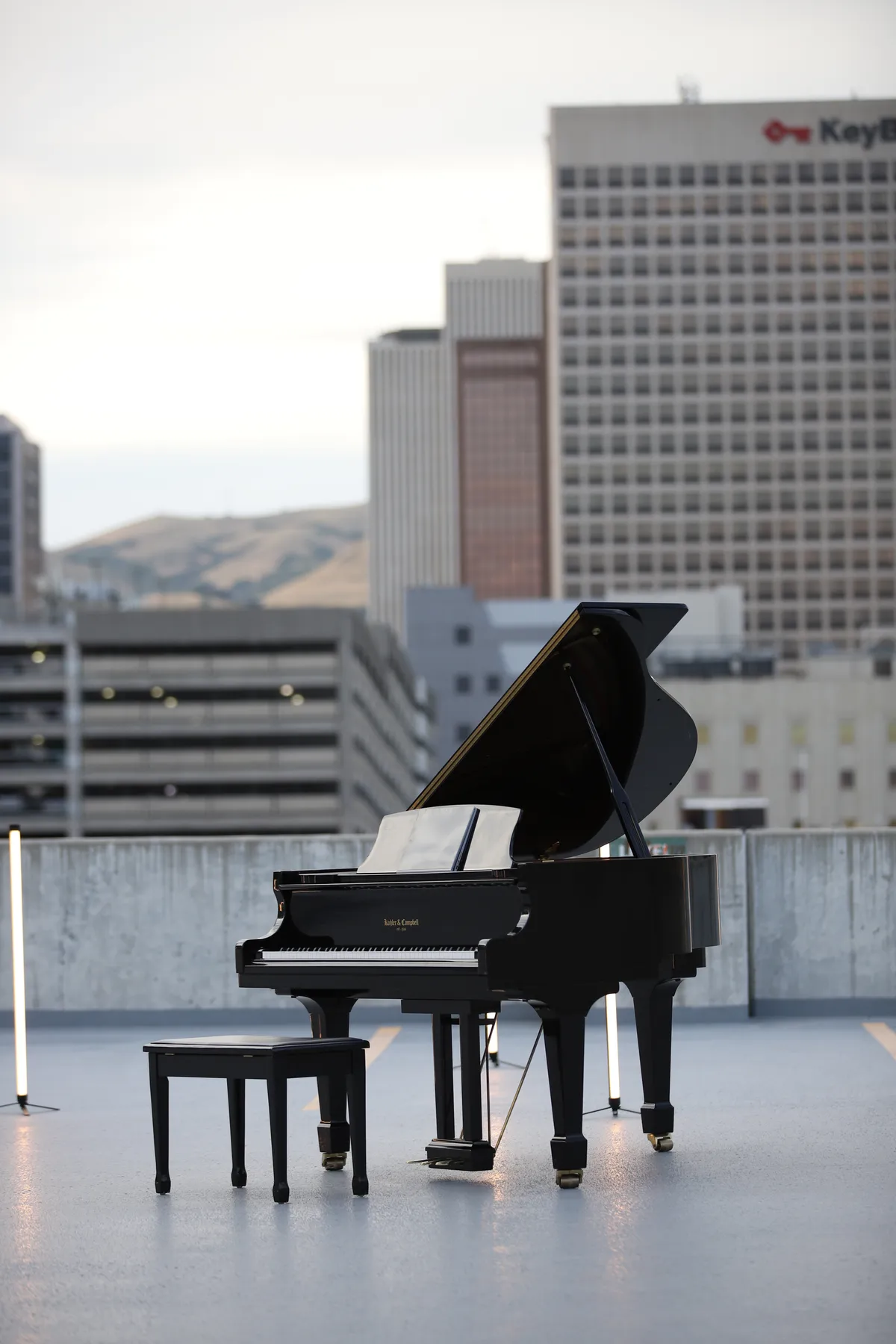 Pianist seated at a black grand piano on the Bonneville Salt Flats, the Silver Island Mountains rising on the horizon.