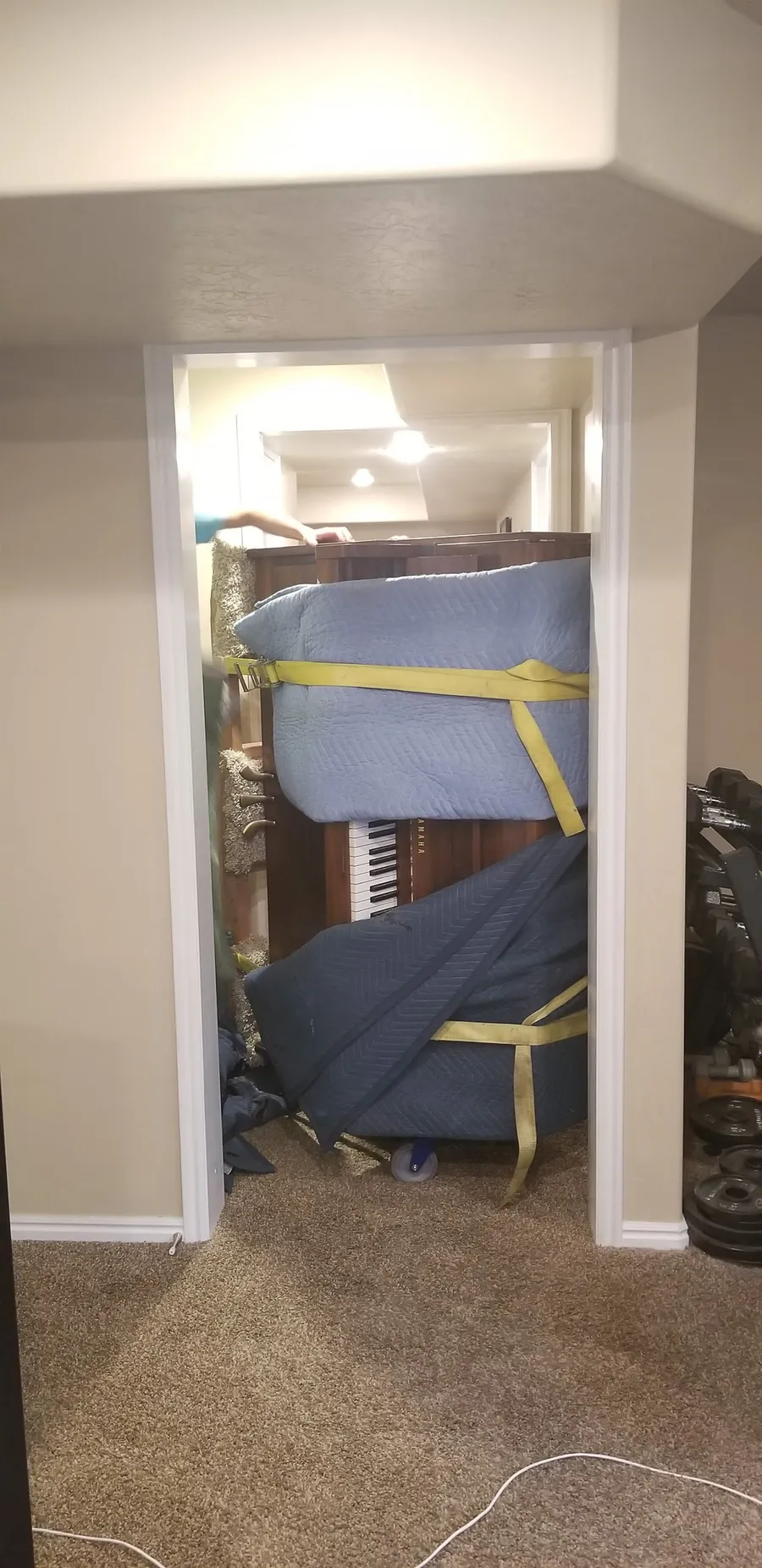A heavily-wrapped piano squeezing through a tight basement doorway during a Salt Lake Valley move.