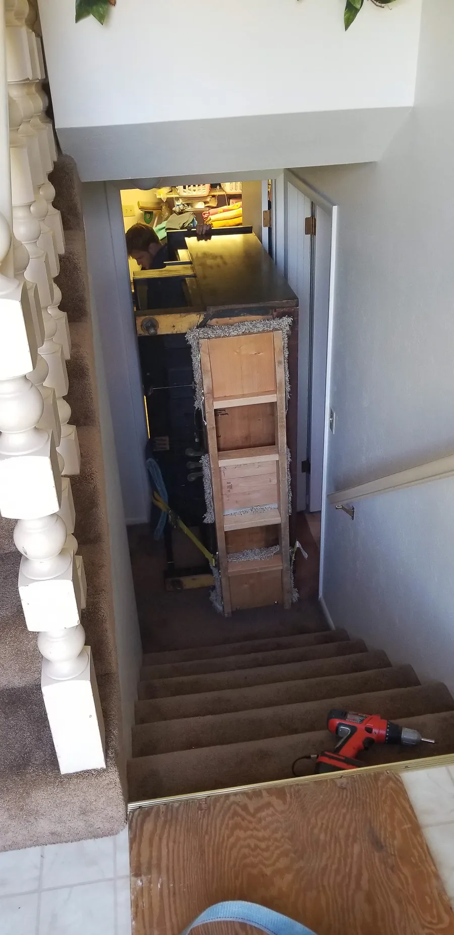 A wrapped piano descending a staircase from above — a basement pull from a Utah residence.