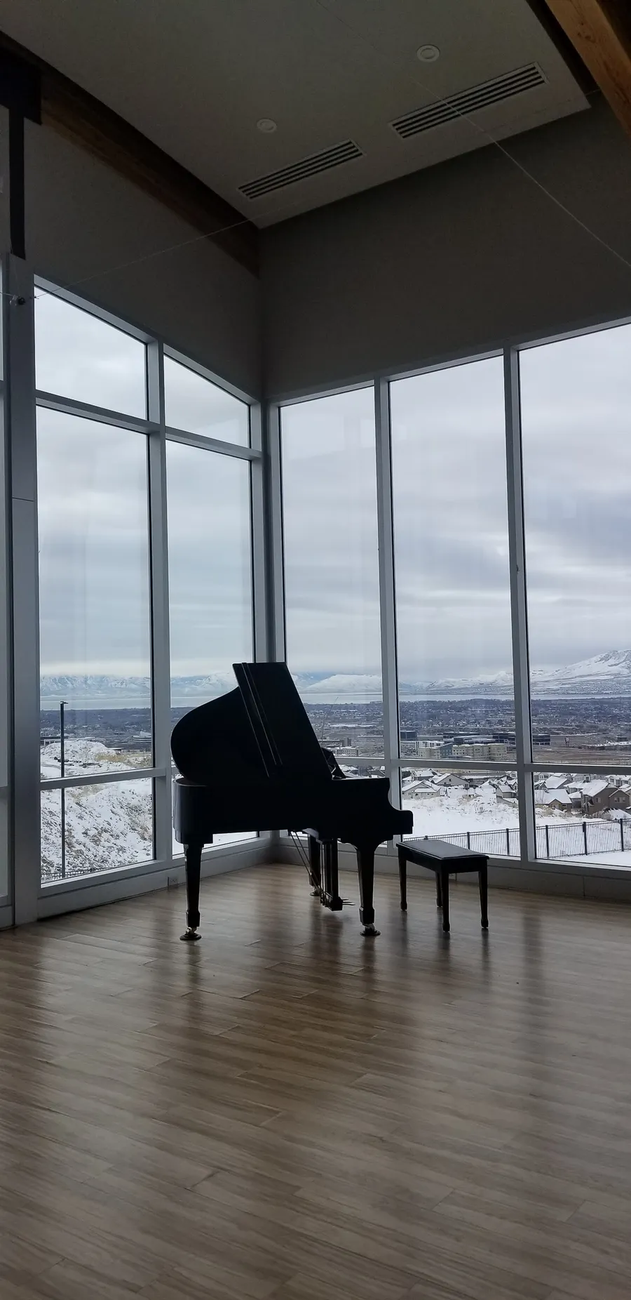 Black grand piano placement near floor-to-ceiling windows with a snowy Wasatch backdrop.