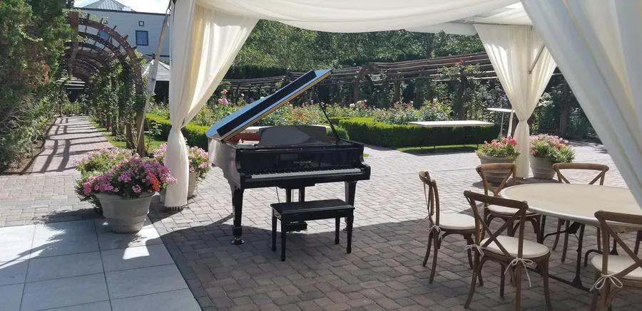 Crew setting up a wrapped piano at an outdoor wedding venue in Utah.