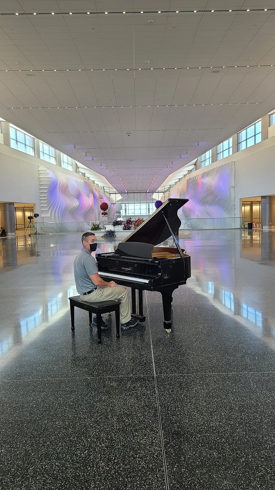 A pianist plays a black grand piano at the Salt Lake City International Airport during the airport opening — a Safe and Sound Pianos rental delivery.
