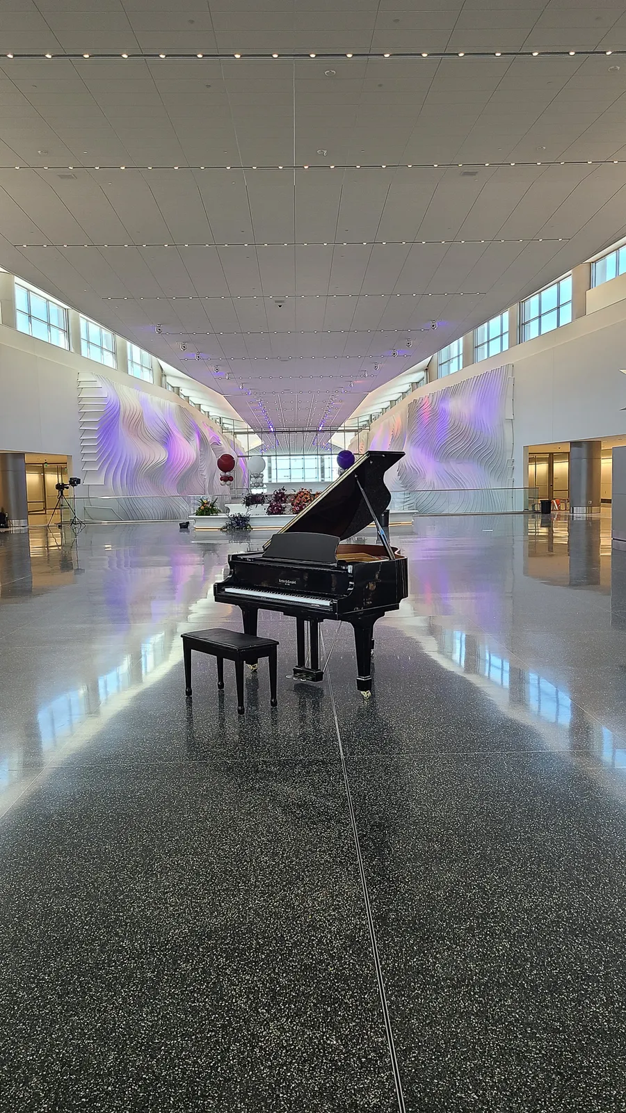 A pianist plays the black grand piano at the Salt Lake City Airport opening, with the modern terminal architecture behind.